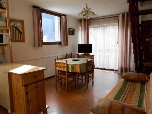 un salon avec une table, des chaises et une télévision dans l'établissement Résidence Hameau Des Thermes I - Appartement 6 personnes proche des Thermes MAE-6104, à Saint-Lary-Soulan