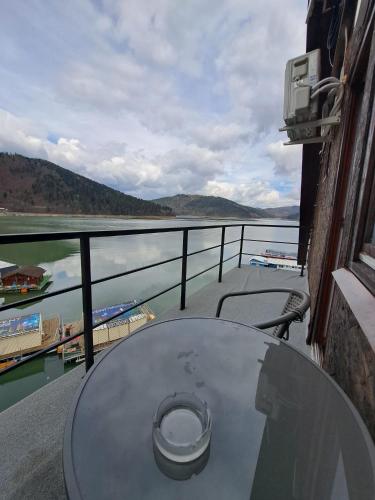 a table on a balcony with a view of the water at Hotel Pescarus Port Bicaz in Bicaz