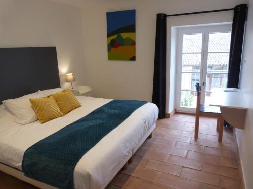 a bedroom with a bed and a desk and a window at Prieuré de Grignan in Grignan