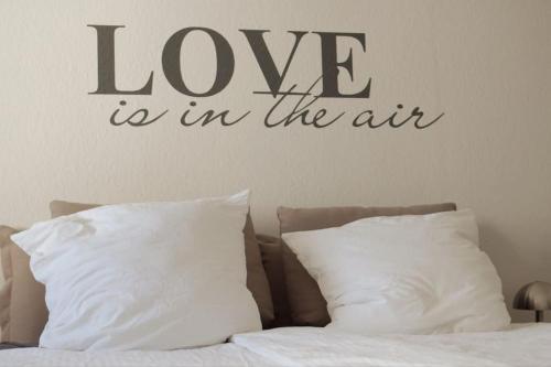a word love is in the air above a bed at Apartment Göhrenglück - groß - zentral - strandnah in Göhren