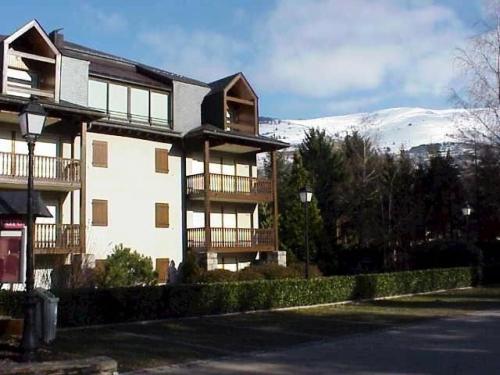 un grand bâtiment avec une montagne enneigée en arrière-plan dans l'établissement Résidence Le Parc - Appartement 6 personnes proche du télécabine et des thermes MAE-6194, à Saint-Lary-Soulan