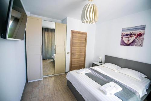 - une chambre avec un grand lit et un miroir dans l'établissement Apartament Katrina - Alezzi Beach - Sea View, à Mamaia Nord – Năvodari