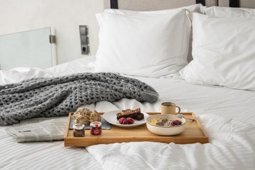 a tray with two plates of food on a bed at Akrotiri Olympus Luxury Suites - Adults Only in Plaka Litochorou