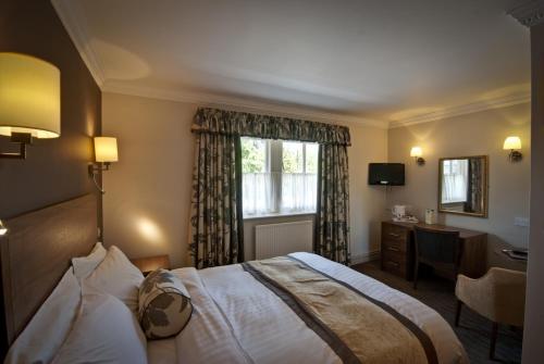 a hotel room with a bed and a desk and a window at Royal Oak Hotel in Betws-y-coed