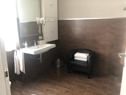 a bathroom with a sink and a black chair at Residenza Segrate Centro Novegro in Segrate