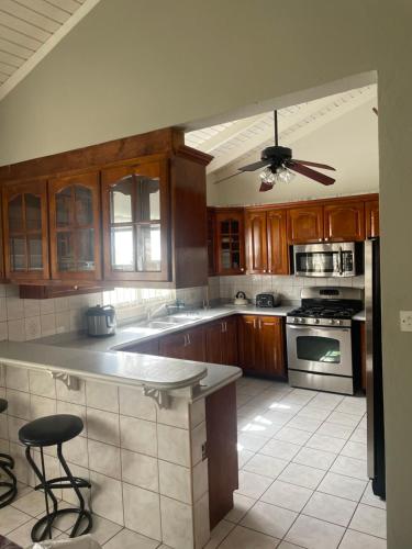 a kitchen with wooden cabinets and a ceiling fan at Mountain view Apartment in Basseterre