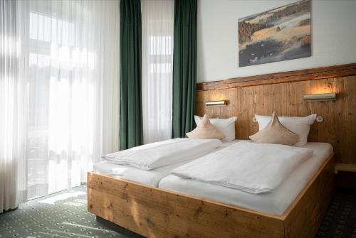 a bedroom with a wooden bed with white sheets and pillows at Manufaktur Boutique Hotel in Stadt Wehlen