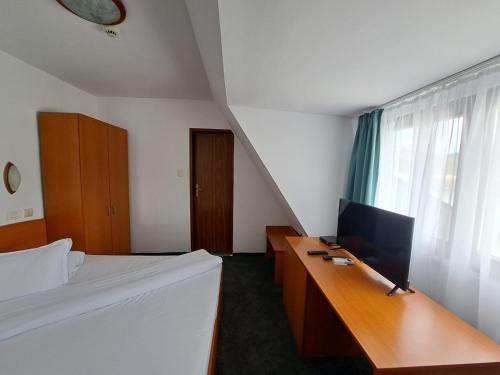 Hotel Pescarus Port Bicaz في بيكاز: غرفة نوم بسرير ومكتب مع تلفزيون