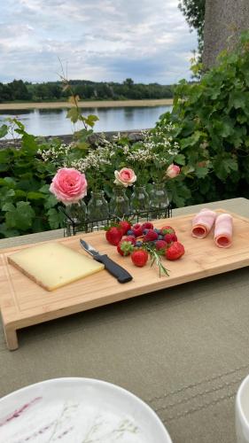 un tagliere di legno con fragole e fiori sopra di Ô Bord de Loire a Denée