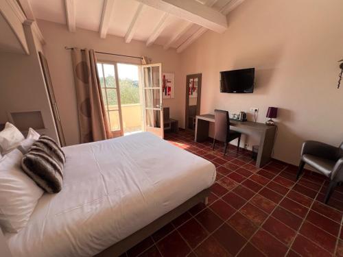 a bedroom with a bed and a desk and a television at Hôtel Restaurant La Bergerie in Aragon