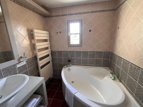 a bathroom with a large tub and a sink at Logis Hôtel Restaurant La Bergerie in Aragon
