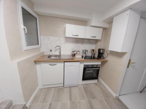 a small kitchen with white cabinets and a sink at PRIMO - Logement 4/6 personnes in Braux