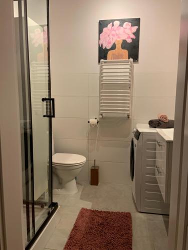 a bathroom with a toilet and a glass shower stall at Garden Place Apartment in Warsaw