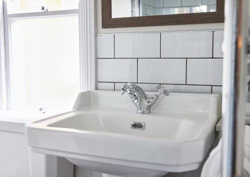 a white sink in a bathroom with a mirror at The Kings Head Wroxham by Greene King Inns in Wroxham