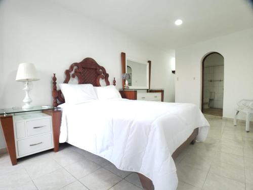 a bedroom with a large white bed and a table at Immaculate 1-Bed Apartment in Cofresi in Las Flores