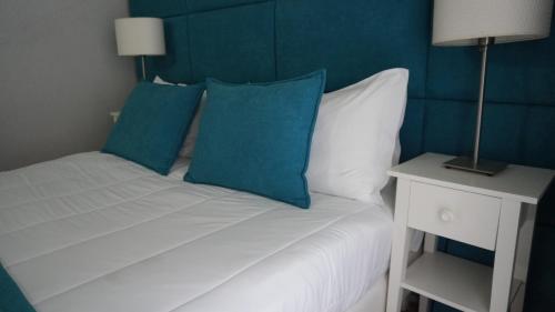 a bed with blue and white pillows and a night stand at Hotel Senhor de Matosinhos in Matosinhos