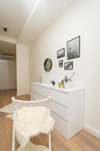 a white room with a white dresser and a chair at Sinfonia Lux 1205 in Sajmište