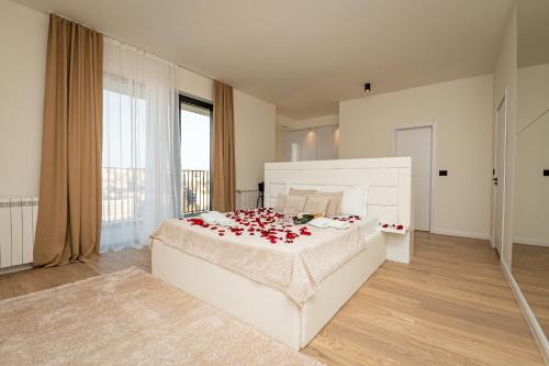 a bedroom with a white bed with red roses on it at Sinfonia Lux 1205 in Sajmište