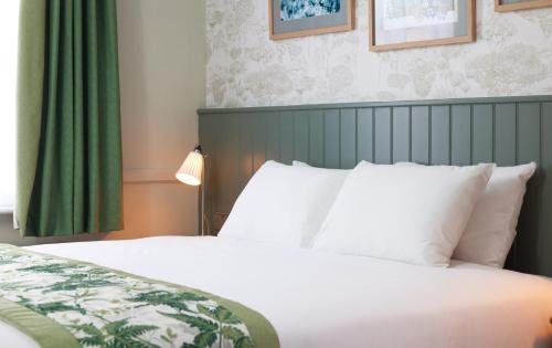 a bedroom with a white bed with a green curtain at The Kings Head Wroxham by Greene King Inns in Wroxham