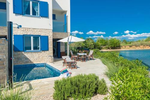 a house with a swimming pool next to a river at Villa Miri Lavender in Privlaka
