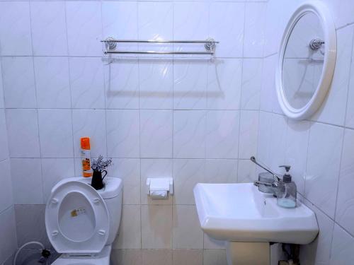 a white bathroom with a toilet and a sink at Olive Escapes in Dar es Salaam