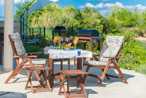 a table with two chairs and a table with wine glasses at Villa Miri Lavender in Privlaka