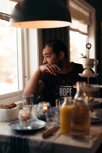 a man sitting at a table looking out a window at Norwegian Wild in Vangsvik