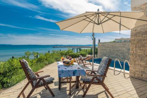 a table with an umbrella and chairs on a patio at Villa Miri Lavender in Privlaka