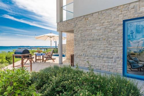 a patio with a grill and chairs and an umbrella at Villa Miri Lavender in Privlaka