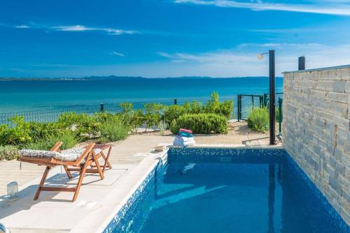 a swimming pool with a table and a chair and the ocean at Villa Miri Lavender in Privlaka