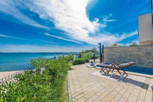 a bench sitting on a sidewalk next to the water at Villa Miri Lavender in Privlaka