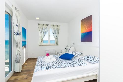 a white bedroom with a bed with blue and white pillows at Villa Miri Lavender in Privlaka
