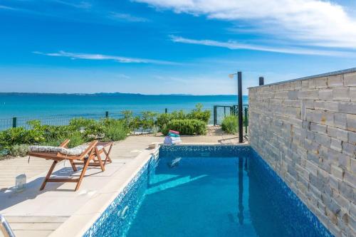a swimming pool with a bench and the ocean at Villa Miri Lavender in Privlaka