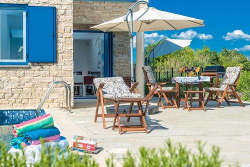 a group of chairs and an umbrella on a patio at Villa Miri Lavender in Privlaka