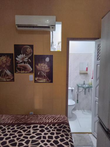 a bedroom with a bed and a bathroom with pictures on the wall at Executive Suite - Ar e Wf Free in Aracaju