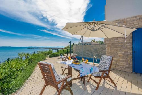 a table and two chairs with an umbrella on a patio at Villa Miri Lavender in Privlaka