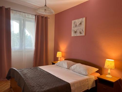 a bedroom with a bed with two lamps and a window at Apartments Villa Mirella 20 m from the sea - free parking in Trogir