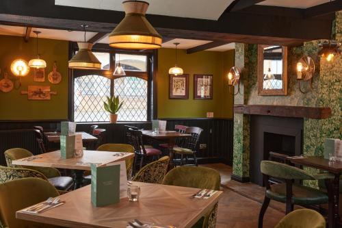 a restaurant with tables and chairs and a fireplace at The Kings Head Wroxham by Greene King Inns in Wroxham