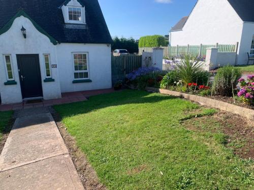 a white house with a yard and a fence at Bayview Holiday Home No 39 by Trident Holiday Homes in Dunmore East