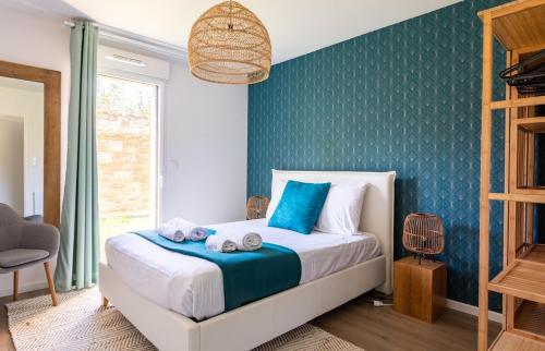 a bedroom with a bed with a blue accent wall at Le Celadon - Joli T3 moderne - 2 chambres avec in Cancale