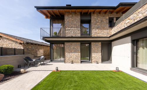 a house with a patio and grass at Cases Cerdanya Mountain Residences in Bellver de Cerdanya 