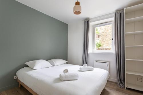 ein Schlafzimmer mit einem weißen Bett und Handtüchern darauf in der Unterkunft La Brise- Joli T2 rénové - Vue Mer - 1 chambre in Cancale