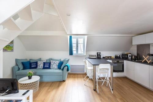 een woonkamer met een blauwe bank en een keuken bij Le Petit Pastel - Joli duplex - Proche de la plage in Saint-Malo