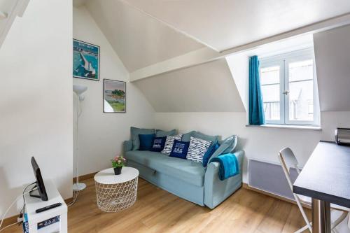een woonkamer met een blauwe bank en een tafel bij Le Petit Pastel - Joli duplex - Proche de la plage in Saint-Malo