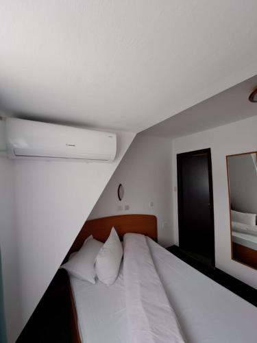 a bedroom with a white bed and a mirror at Hotel Pescarus Port Bicaz in Bicaz