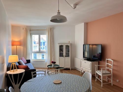 a living room with a table and a tv at L'Echappée douce - Mer & Port à pied in Courseulles-sur-Mer