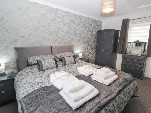 a bedroom with a bed with white towels on it at The Hideaway Waverton Villa in Wigton
