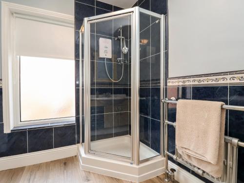 a glass shower in a bathroom with black tiles at 46 The Promenade in Withernsea