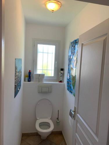 La salle de bains est pourvue de toilettes blanches et d'une fenêtre. dans l'établissement Maison entre terre et mer Vue sur mer Grande terrasse, à Mucchio