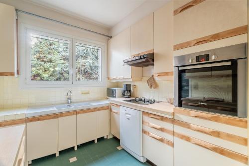 une cuisine avec des armoires blanches et une fenêtre dans l'établissement Les Aiguadines par Dodo à Cassis, à Cassis